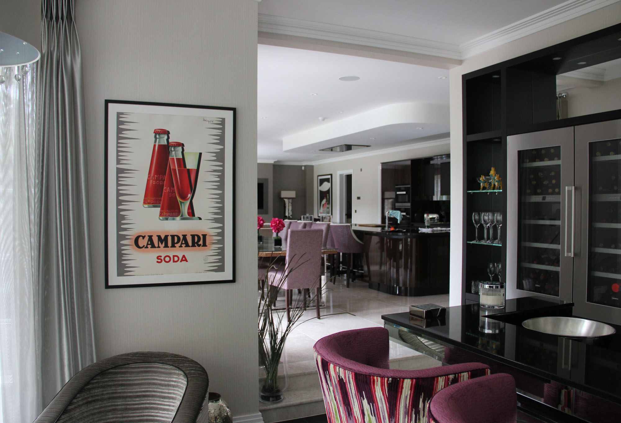Sleek, Art Deco style living and dining area with Campari poster; red, purple, black, grey