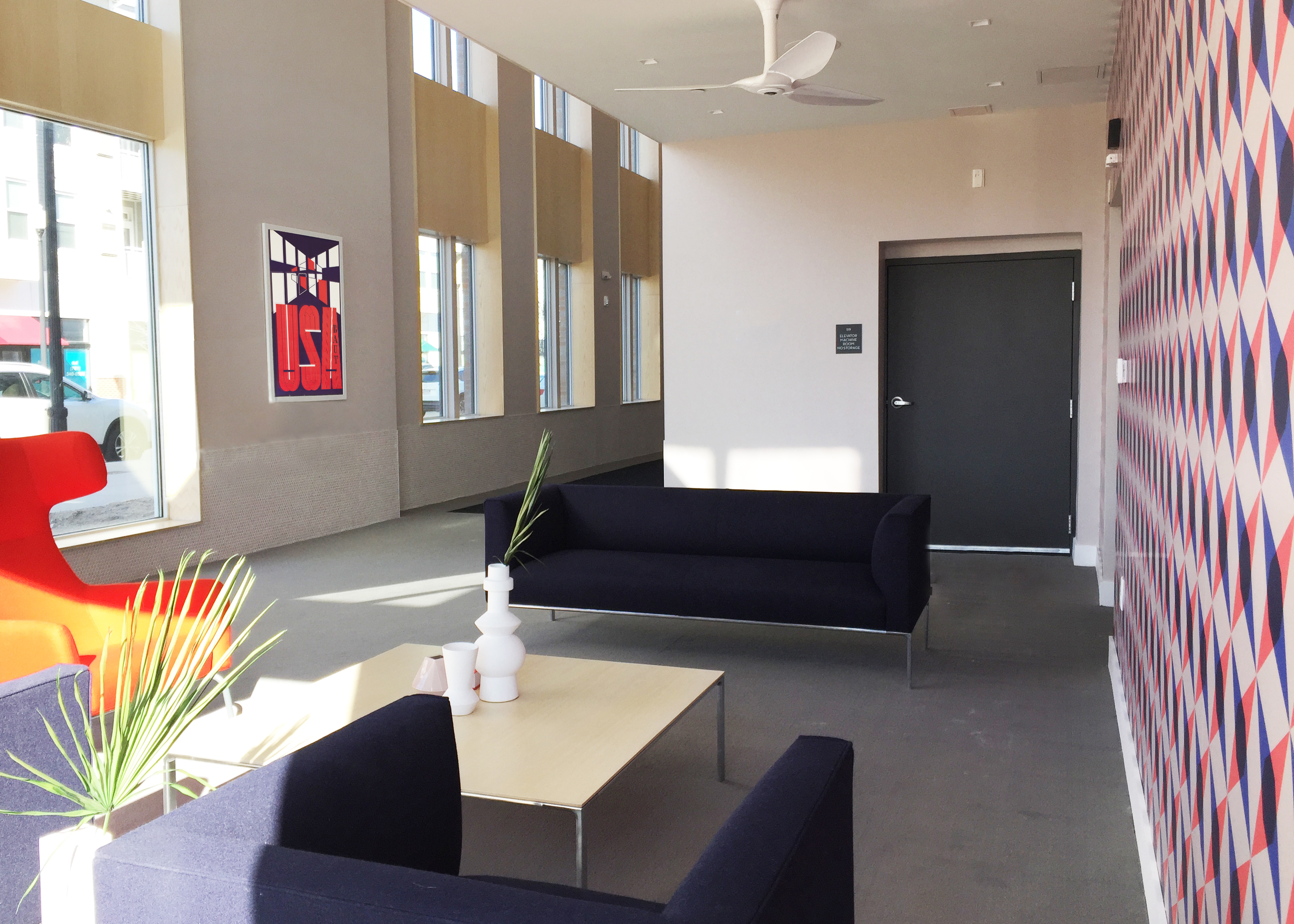 large hallway with modern furniture, accent wall, and USA poster; black, white, blue, red